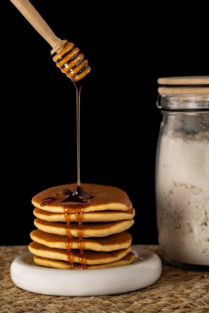 photo culinaire avec des pancakes et du miel qui coule dessus
