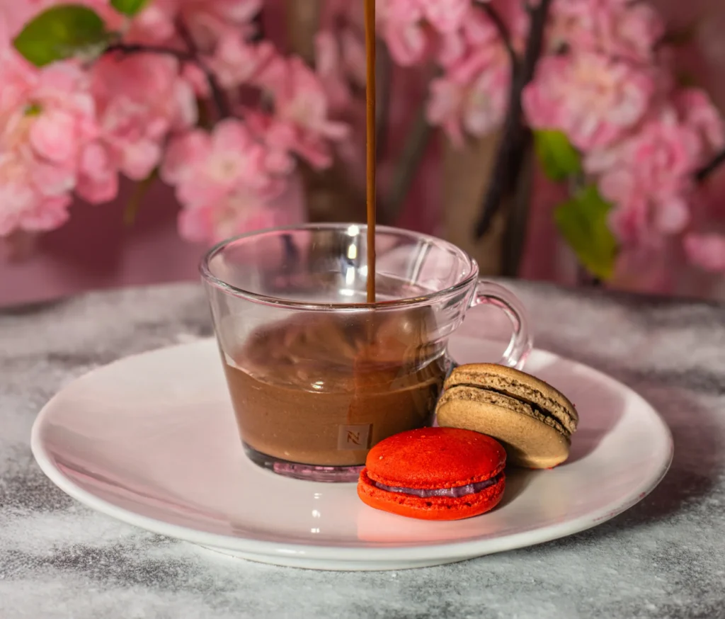 photo culinaire d'un chocolat chaud qui coule dans la tasse et des macarons