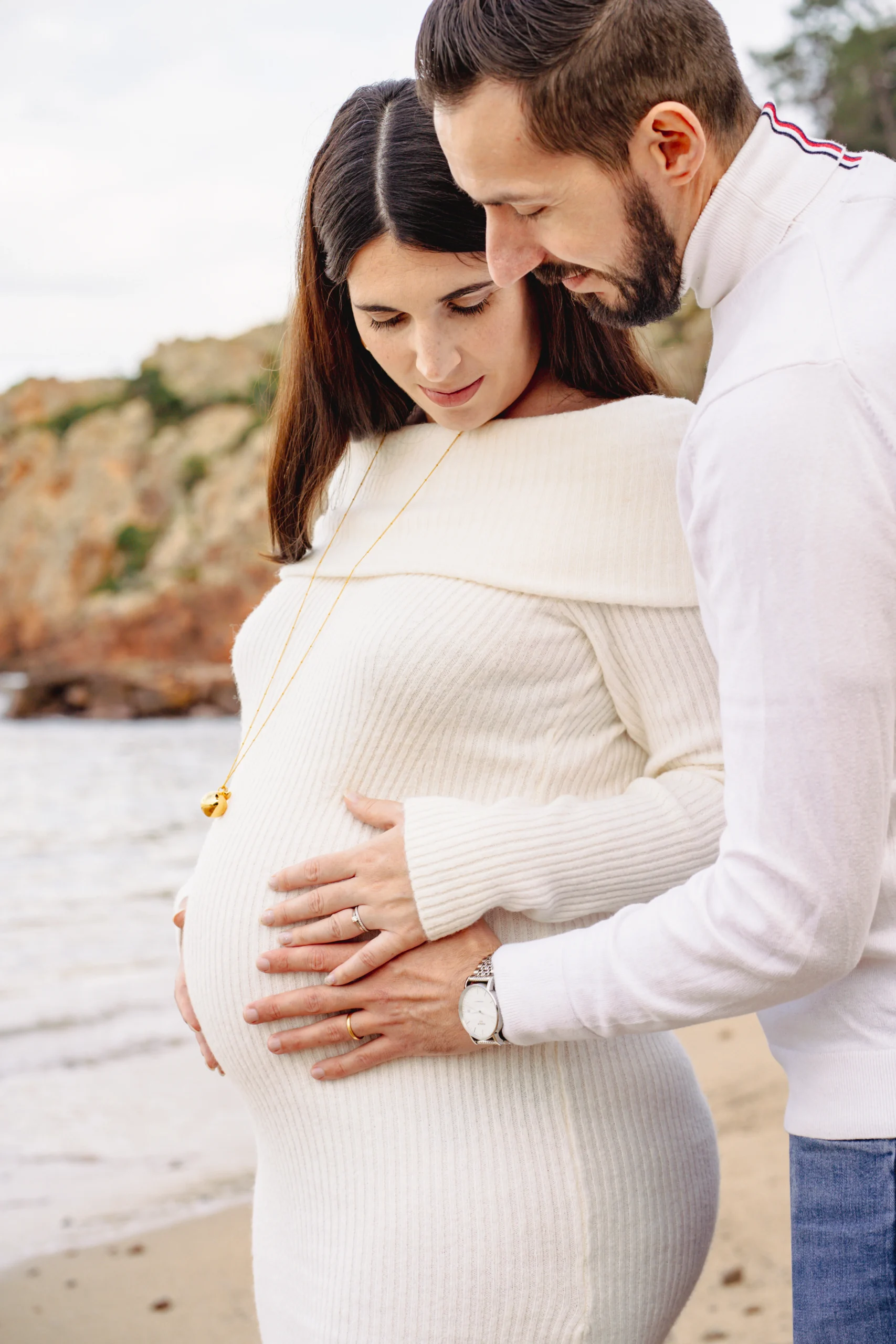Couple attendant un enfant lors d’une séance photo de grossesse sur la plage
