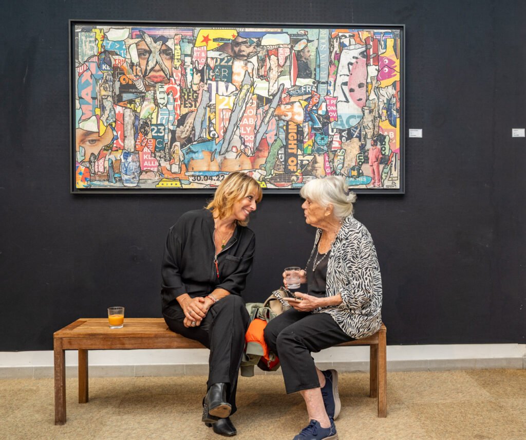 2 dames qui échangent lors d'un vernissage de tableaux artistiques