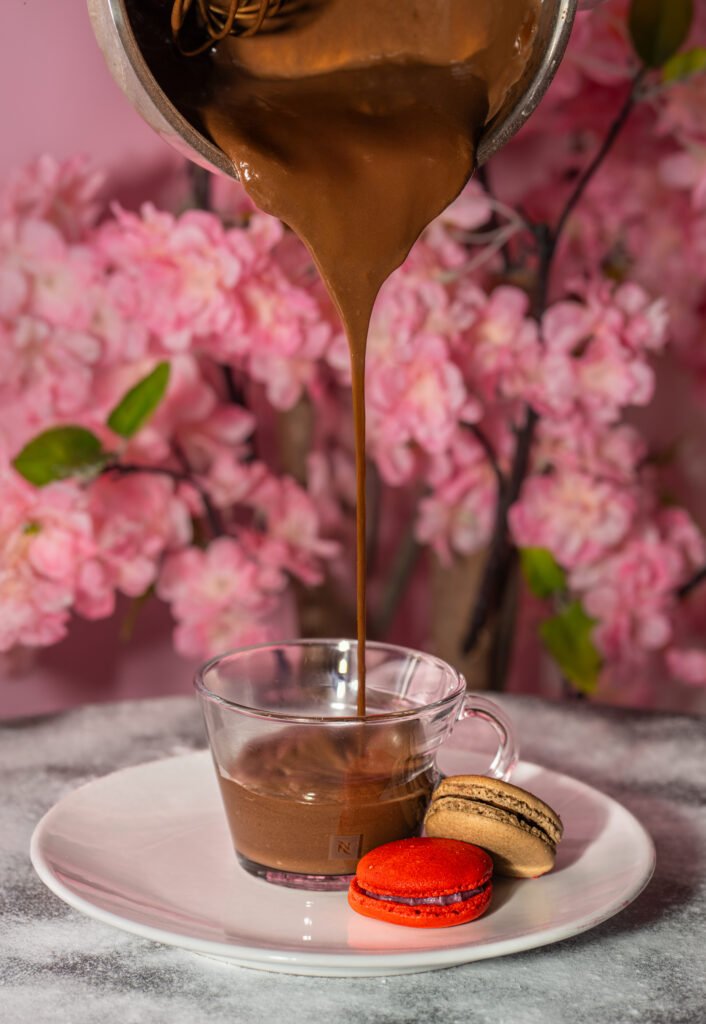 photo culinaire d'un chocolat chaud qui coule dans la tasse et des macarons